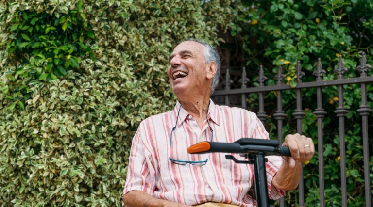 Man with pink and white shirt riding Carbon scooter outside