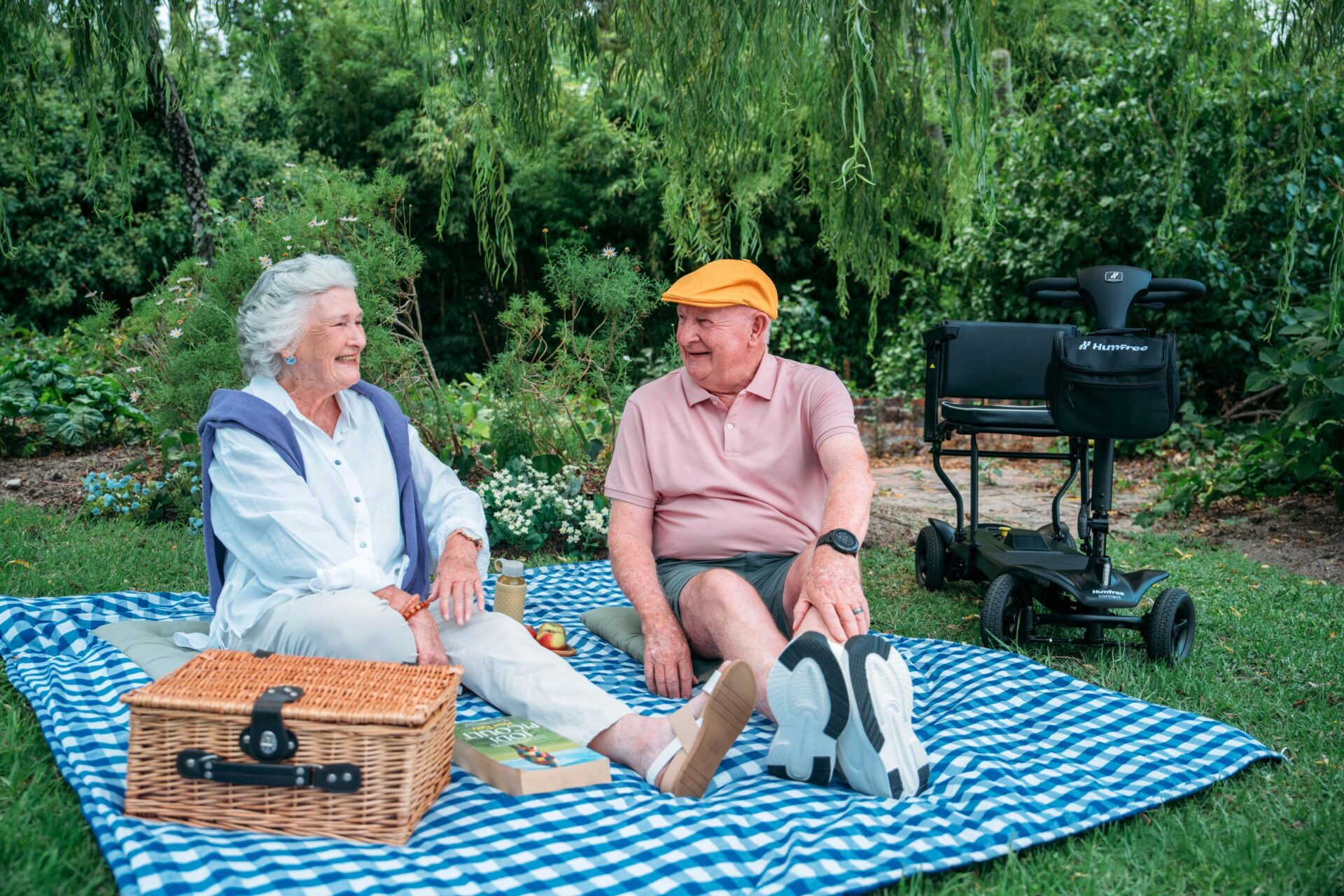 Couple having a picnic with their Humfree Connect scooter parked next to the picnic blanket