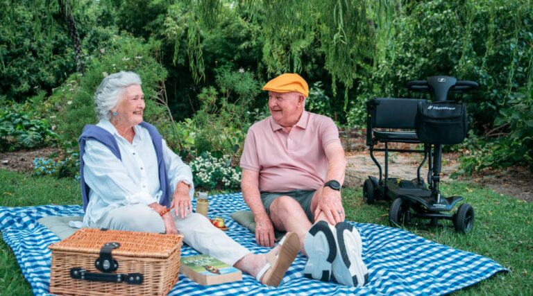 Couple having a picnic with their Humfree Connect scooter parked next to the picnic blanket
