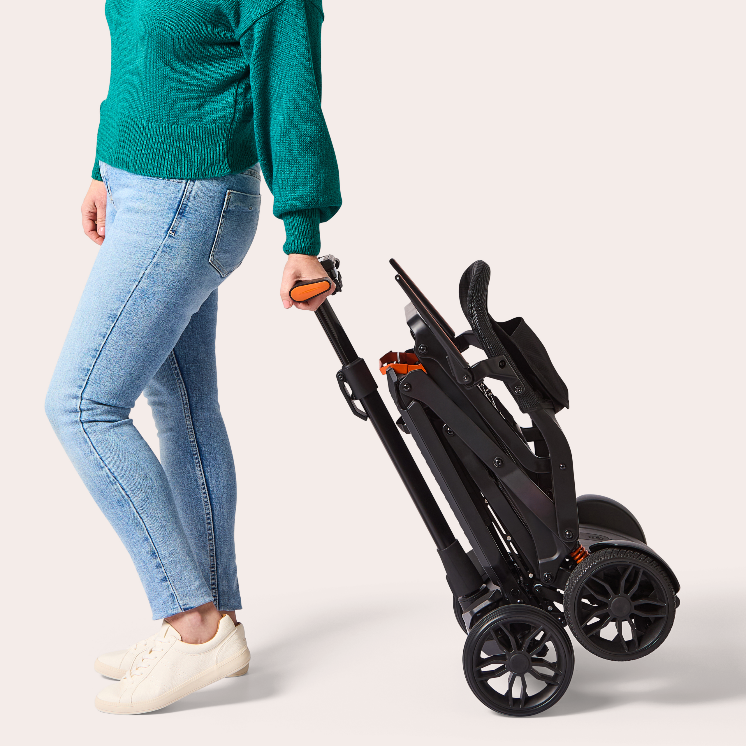 Woman pulling folded charcoal Humfree carbon scooter on back wheels